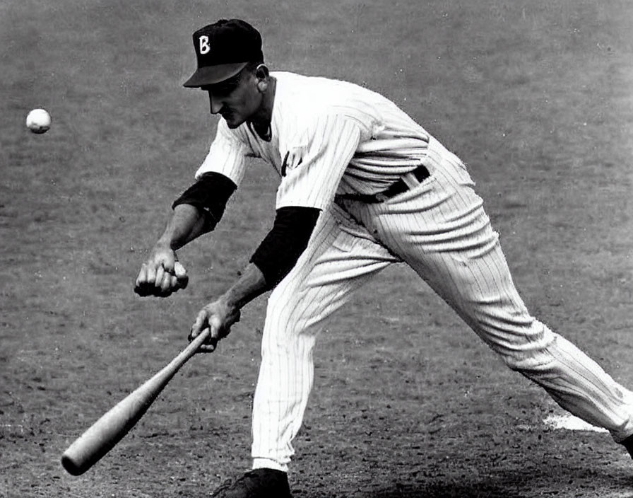 Monochrome image of baseball player bunting with "B" cap