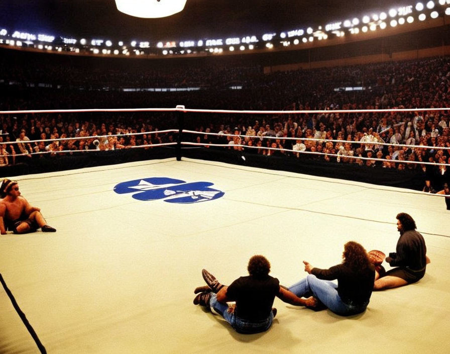 Wrestling ring with wrestlers and crowd in indoor arena