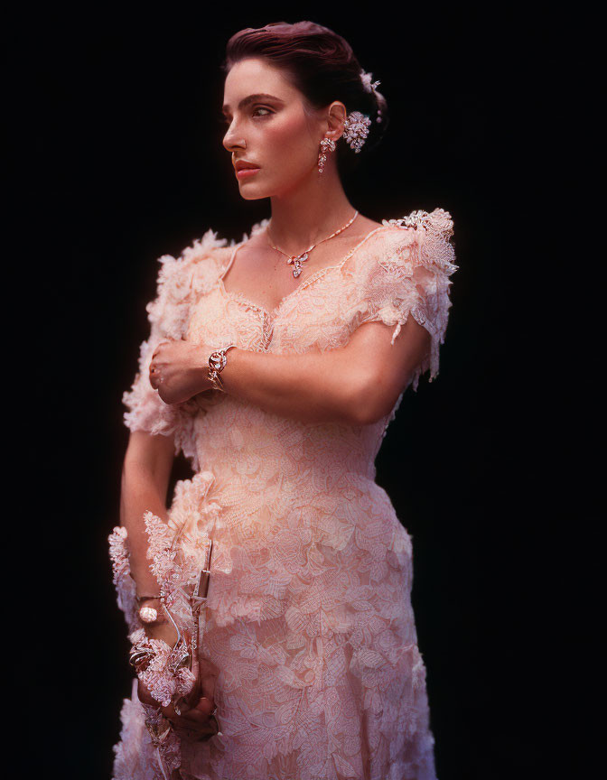 Elegant woman in lace dress with floral details and jewelry on dark background