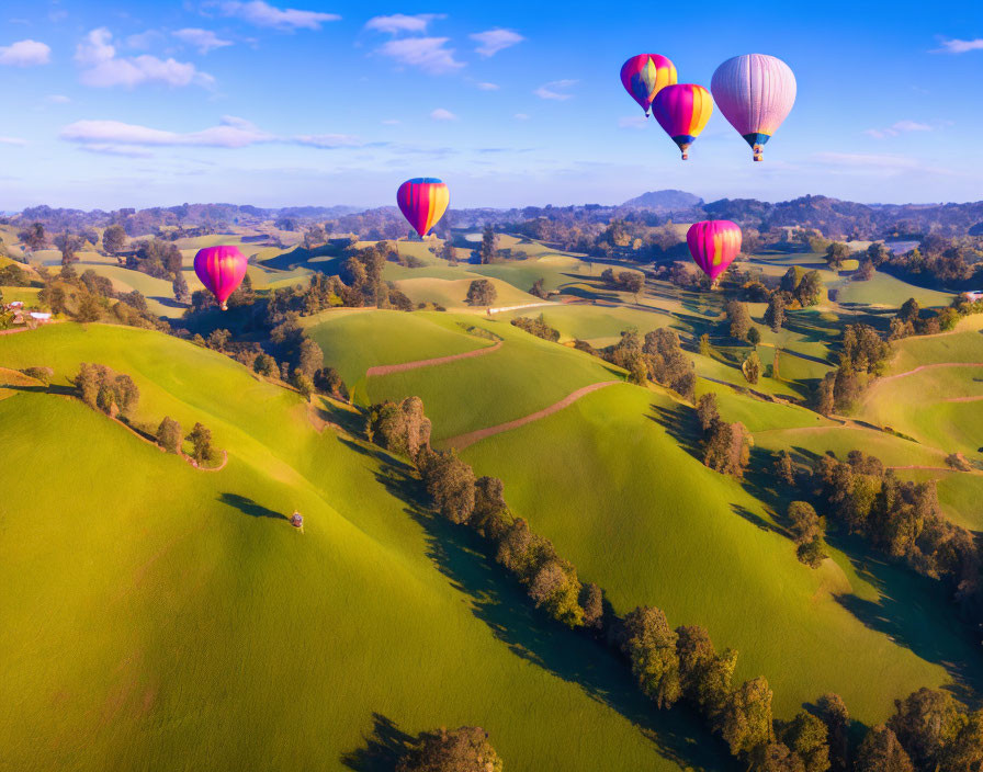 Scenic aerial view of hot air balloons over green hills