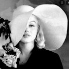 Monochrome portrait of a woman with striking makeup and elegant flower-adorned hat