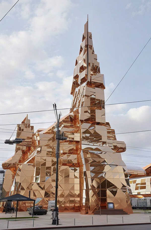 Golden art installation: Futuristic tower with geometric shapes in urban setting