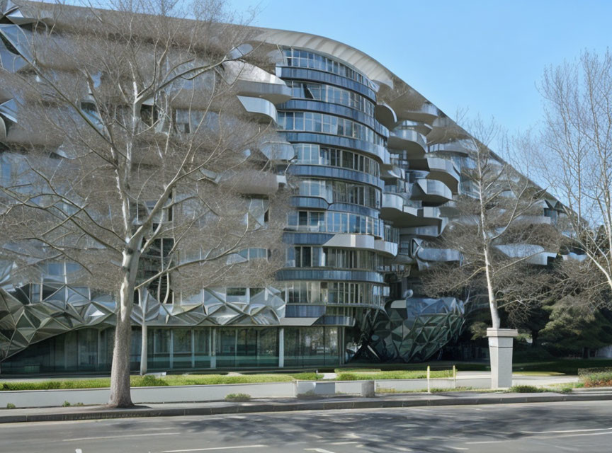 Contemporary multi-story building with wavy glass facade and geometric patterns near a street with bare trees under