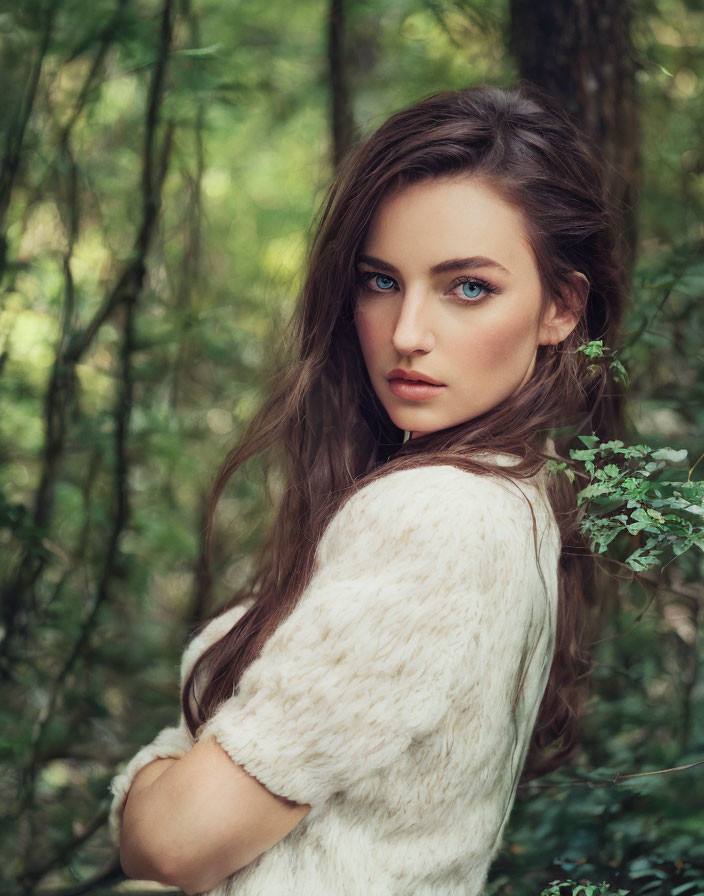 Blue-eyed woman in white sweater in lush green woodland