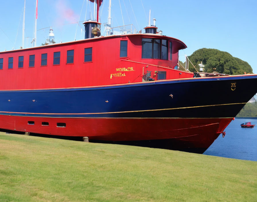 Large red and blue boat named "MV Pentalina" docked in calm blue water with green