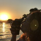 Split image of person on hill at sunset & hand holding hat with starry sky and cosmic face.