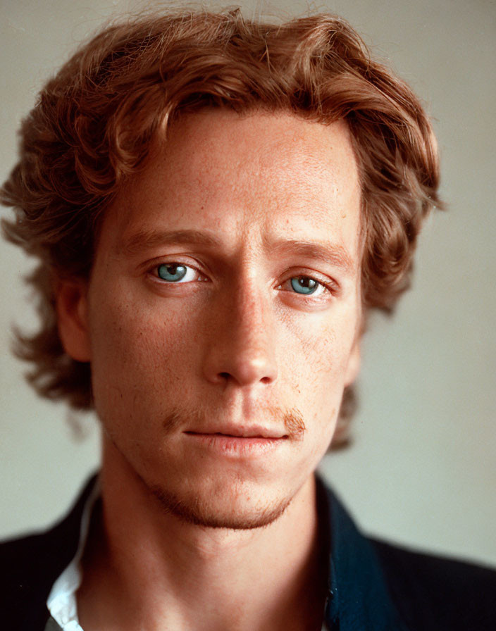 Man with Curly Hair, Blue Eyes, and Mustache in Black Jacket and White Shirt