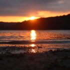 Vivid Sunset Reflections on Lake Surface and Silhouette Hills