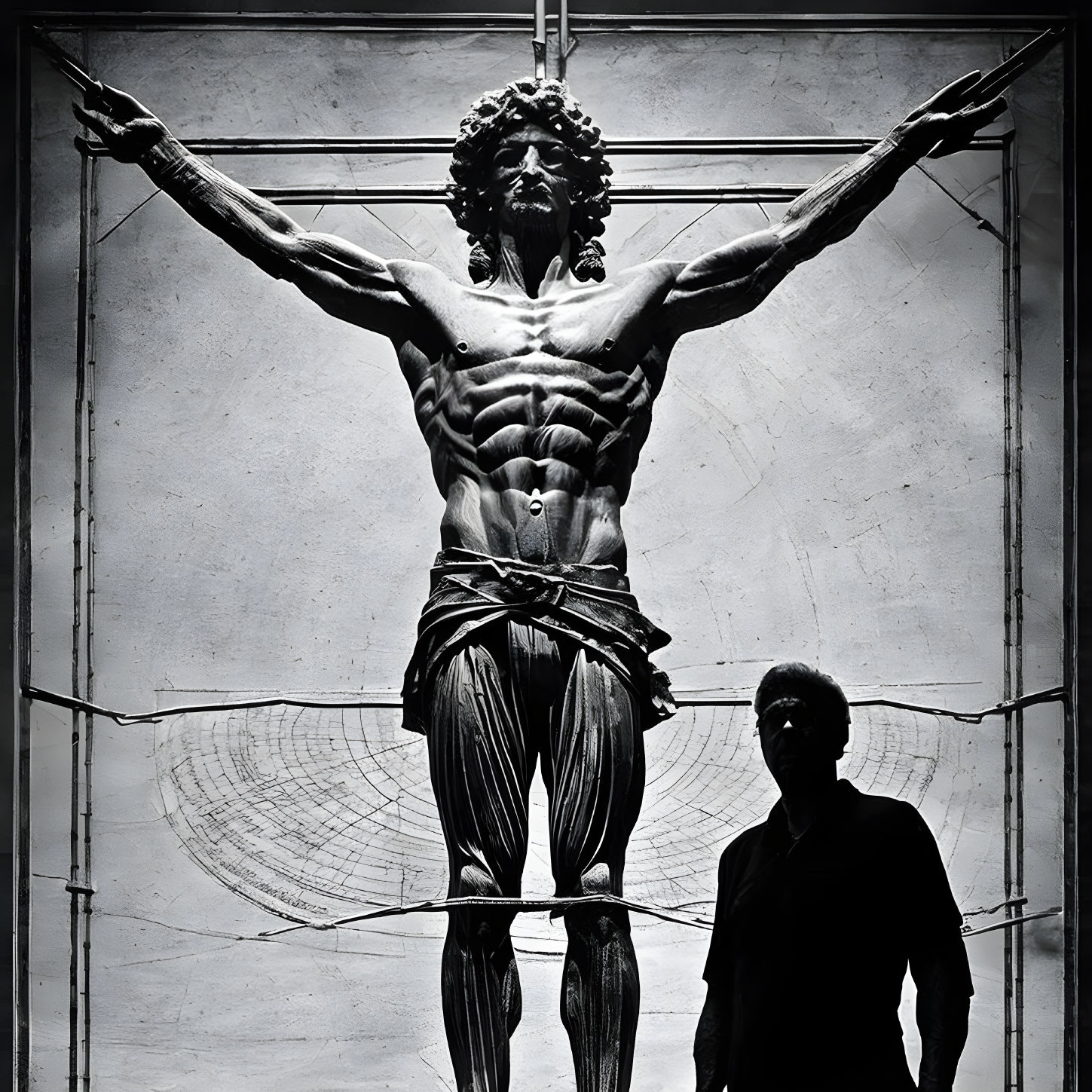 Person in shadow before dramatic, muscled cruciform sculpture with detailed lighting.