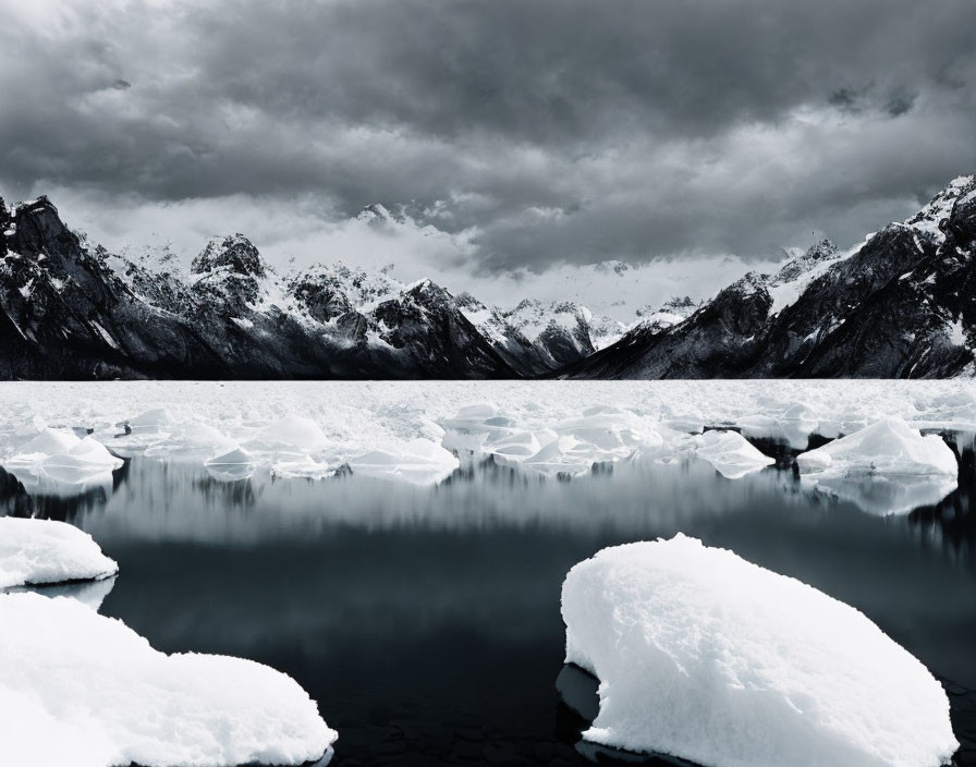 Tranquil lake with icebergs, snow-capped mountains, moody sky