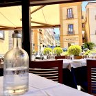 Quaint European street outdoor dining with wine glasses, cutlery, and yellow umbrellas