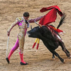 Matador in traditional suit faces charging bull in watercolor backdrop