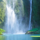 Tranquil waterfall surrounded by green foliage and sunlight mist