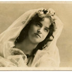 Dark-haired woman with gold jewelry in ornate setting.