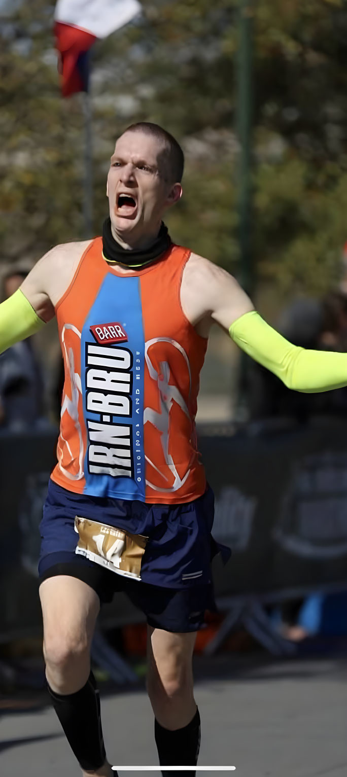 Male runner with strained expression in mid-stride during race