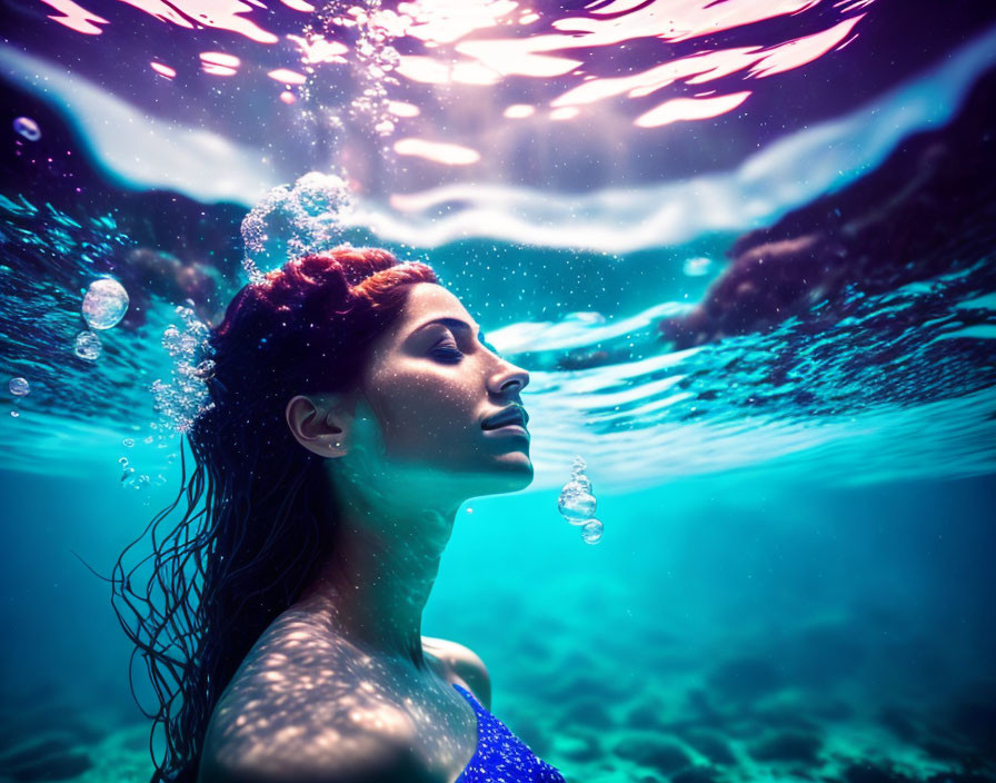 Red-Haired Woman Swimming Underwater with Sunlight and Bubbles