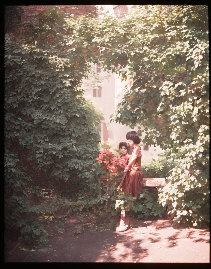 Woman in Red Dress with Flowers by Ivy-Covered Wall