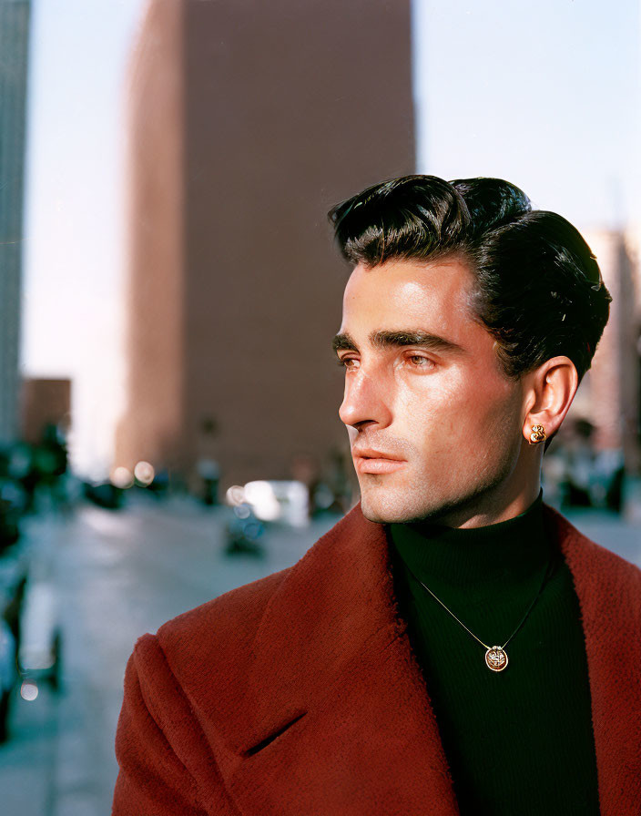 Dark-Haired Man in Red Coat and Earring Outdoors with Building Background