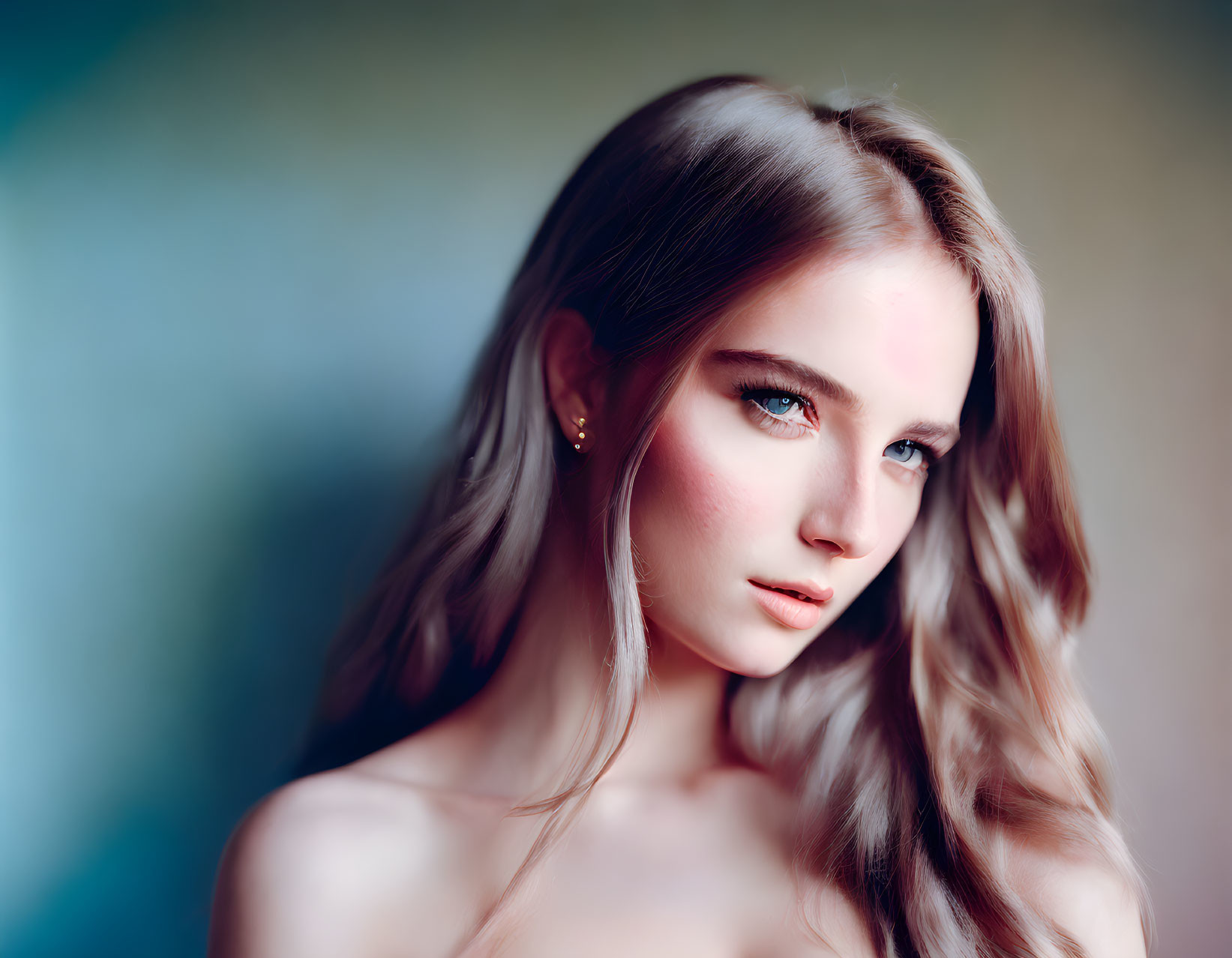 Young woman portrait with long wavy hair and blue eyes on soft blue backdrop