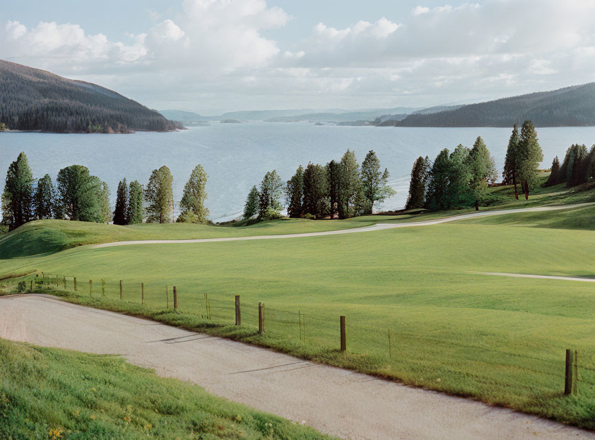 Tranquil lake nestled among lush green hills under partly cloudy sky