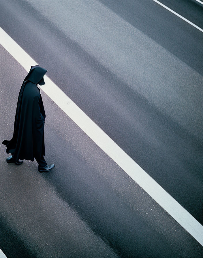 Mysterious figure in black cloak crossing zebra on empty road