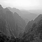 Layered Peaks of Misty Mountain Range with Yellow Foliage and Soft Hazy Sky