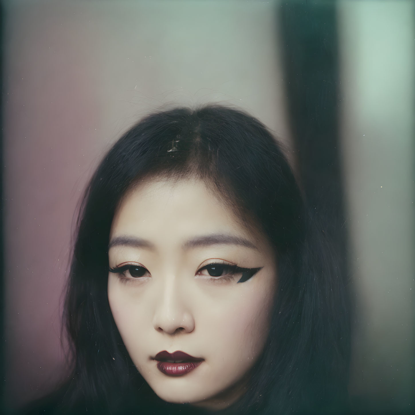 Portrait of woman with bold eyeliner and dark lipstick in serious gaze.