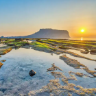 Tranquil sunrise landscape with reflective water & rolling hills