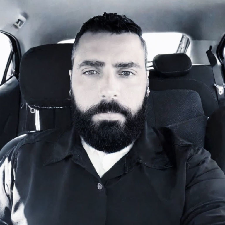 Bearded man in car with serious expression in black and white photo