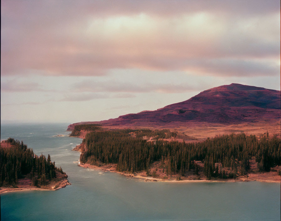 Tranquil river landscape with forest, mountain, and colorful sky