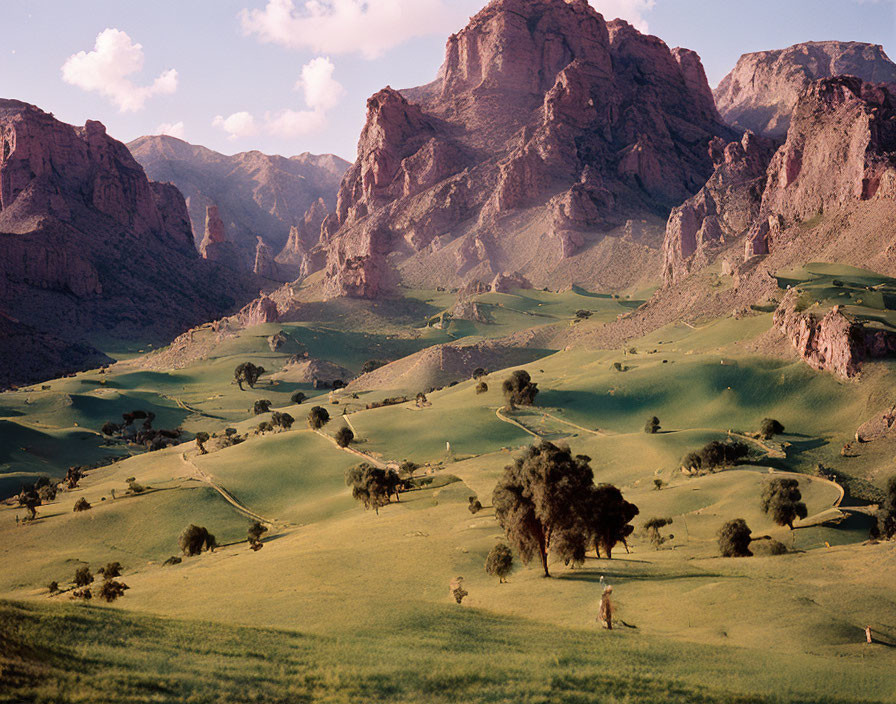 Scenic landscape: green hills, trees, rocky mountains, blue sky