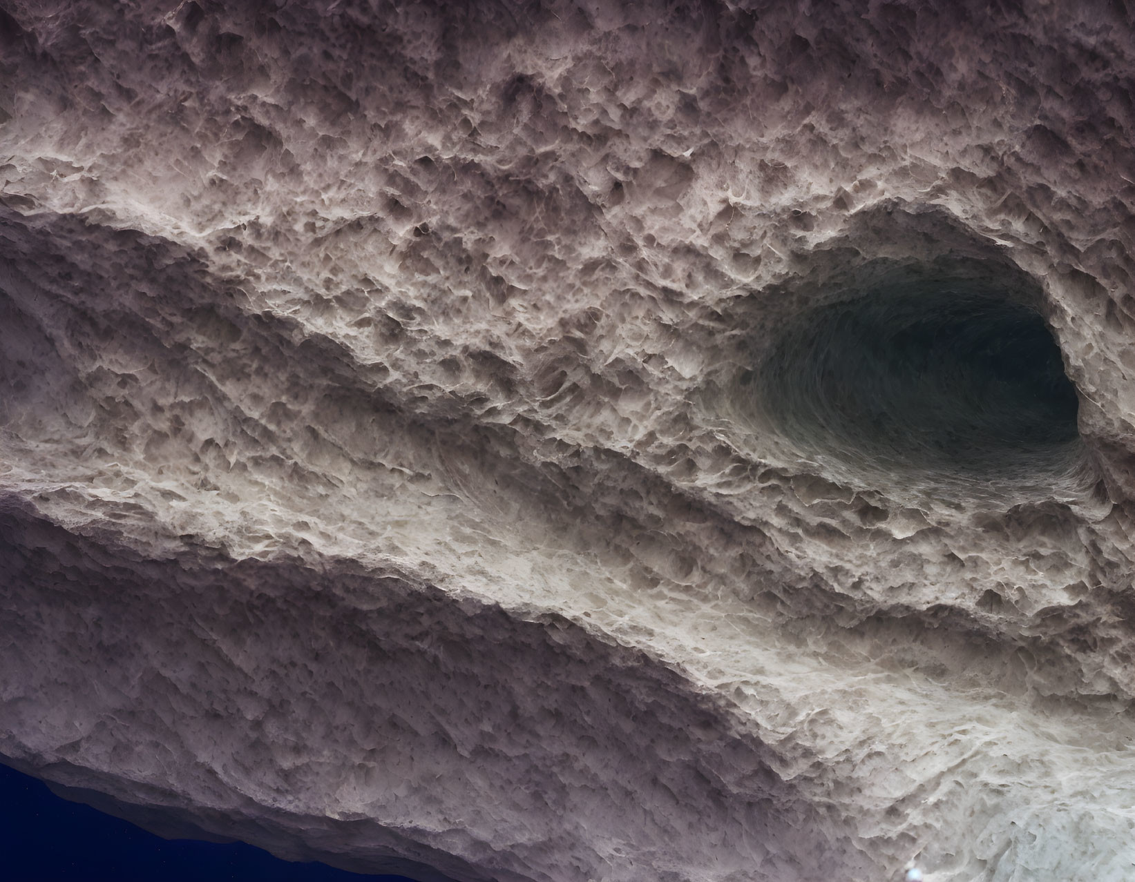 Rock layers in textured cave ceiling with eye-shaped cavity.