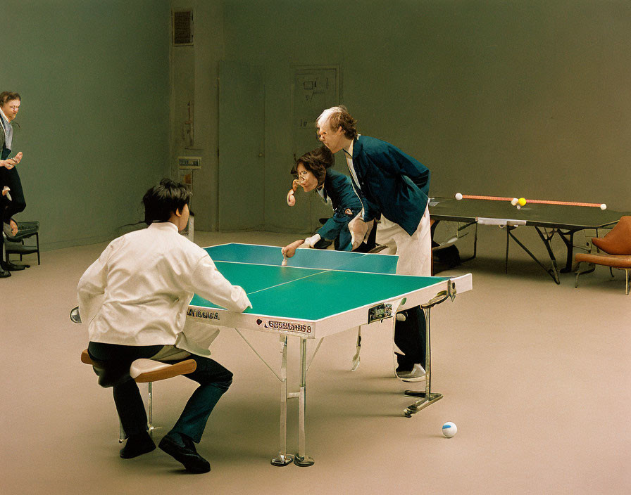 Indoor setting with four people playing table tennis