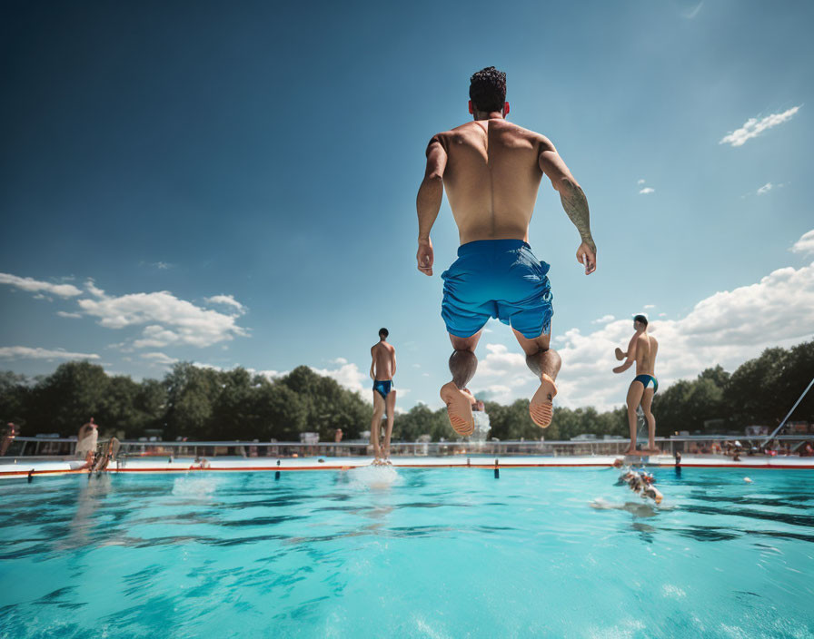 Person in Blue Swim Shorts Jumping into Outdoor Swimming Pool