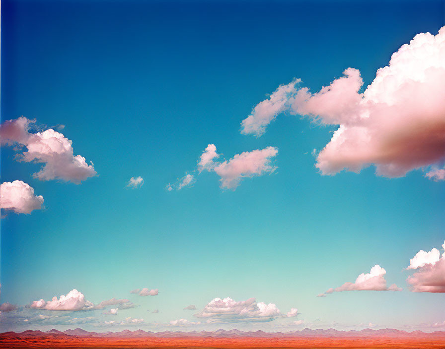 Scenic desert landscape with fluffy clouds and red sands