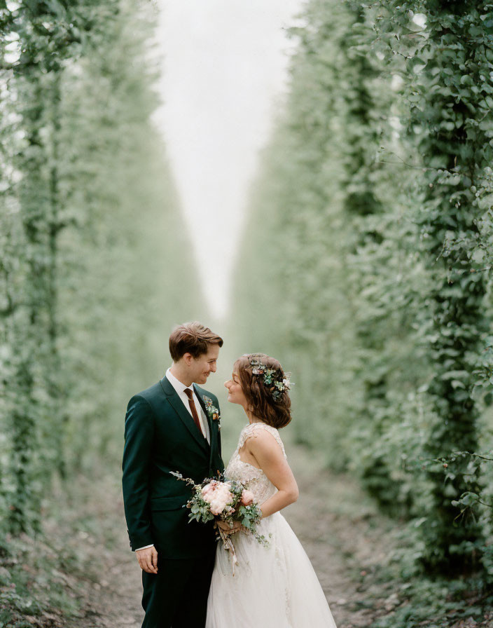 Wedding couple in attire on serene tree-lined path surrounded by greenery