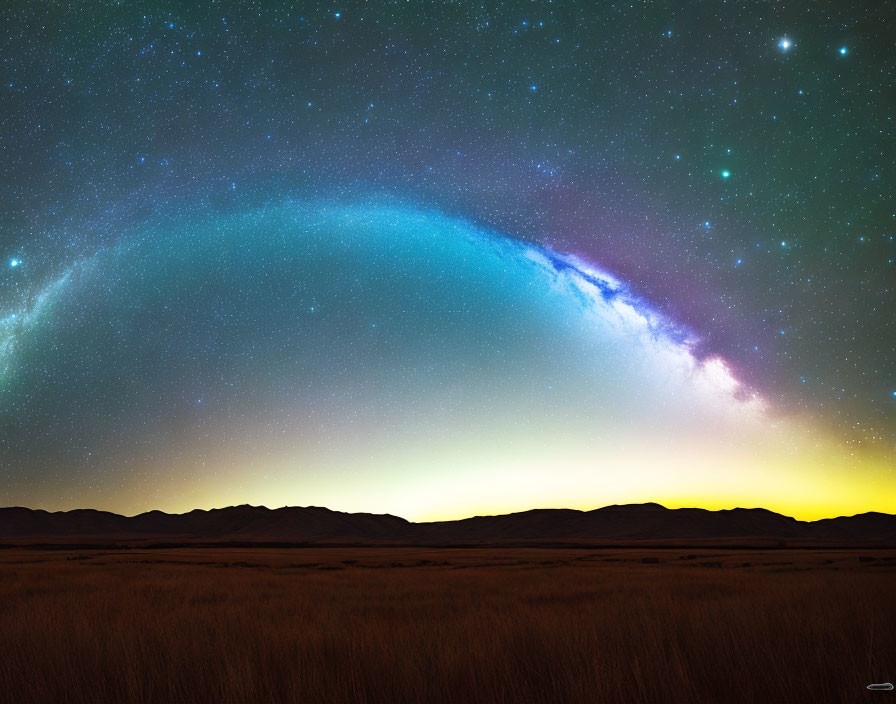 Scenic starry night sky over mountain range and field