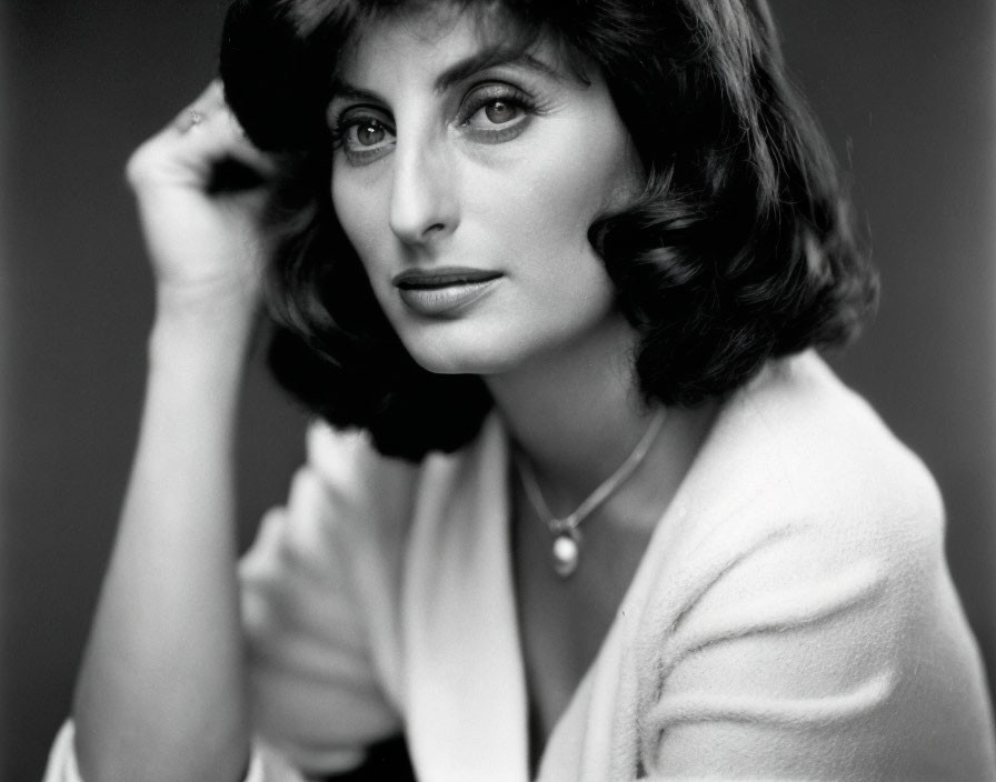 Shoulder-length hair woman holding hat, in light jacket.