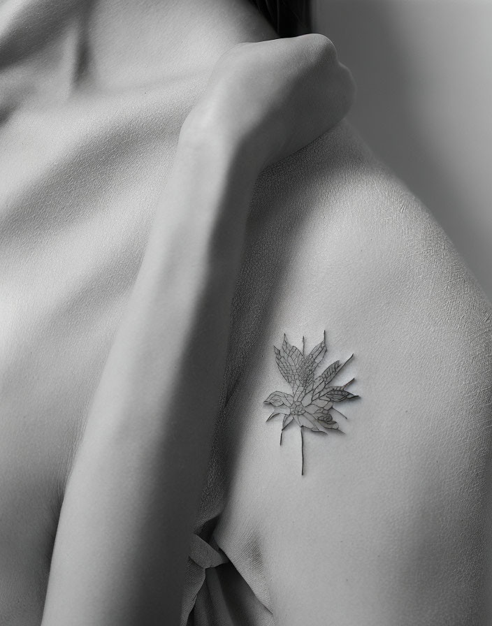 Monochrome photo of a person's shoulder with floral tattoo and draped fabric