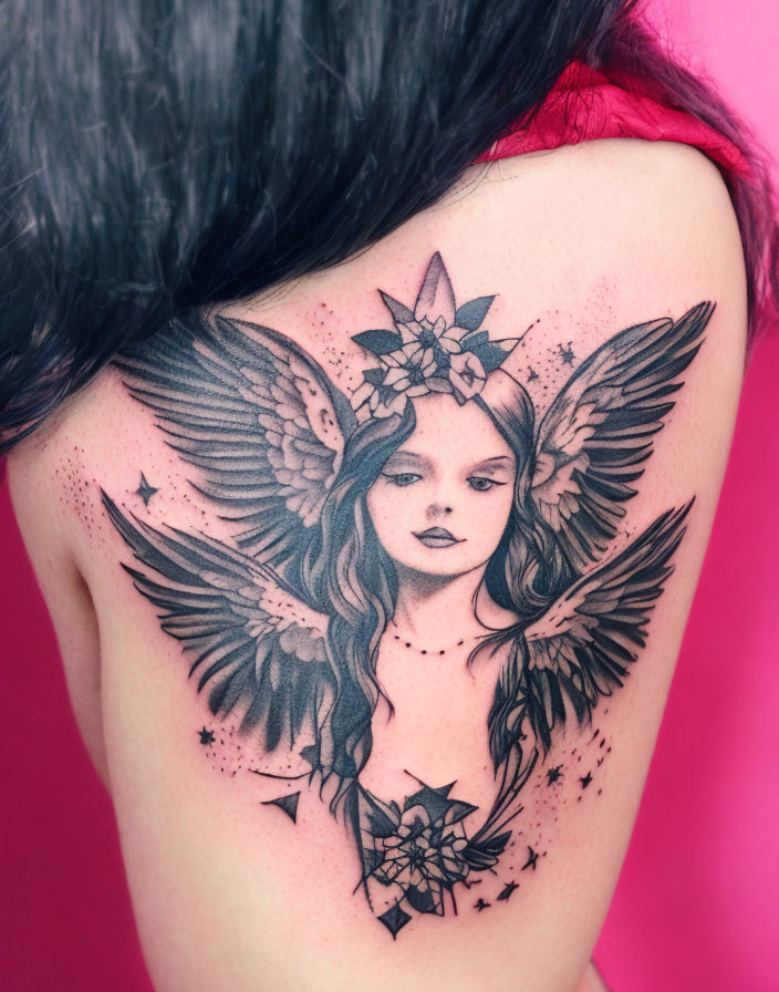 Detailed angelic figure back tattoo with wings, stars, and florals on pink background