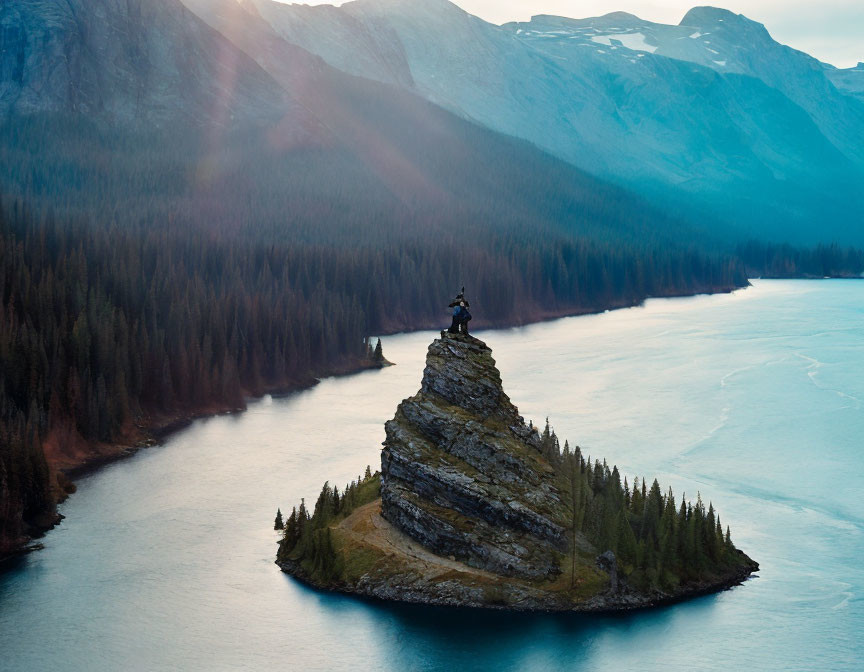 Person on Rock Pinnacle in Frozen Lake at Dusk