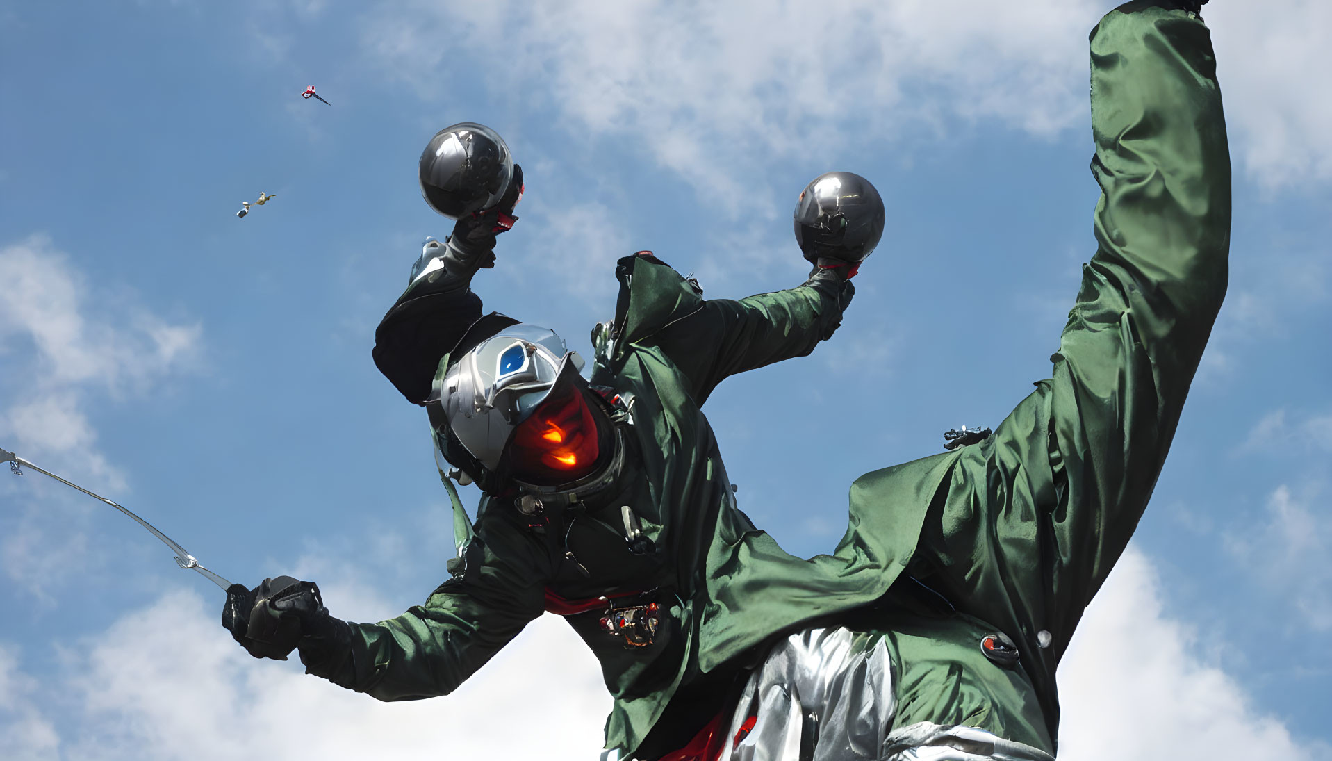 Skydiver in green suit with open visor helmet holding domed objects in freefall