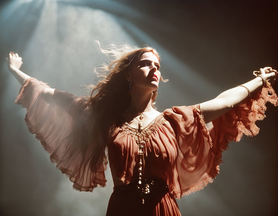 Woman in flowing dress with dramatic sleeves posing confidently under spotlight