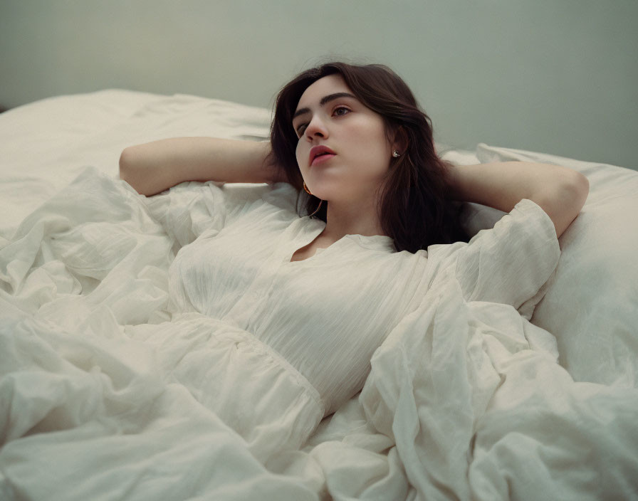 Woman in White Dress Relaxing on Crumpled Bed Sheet