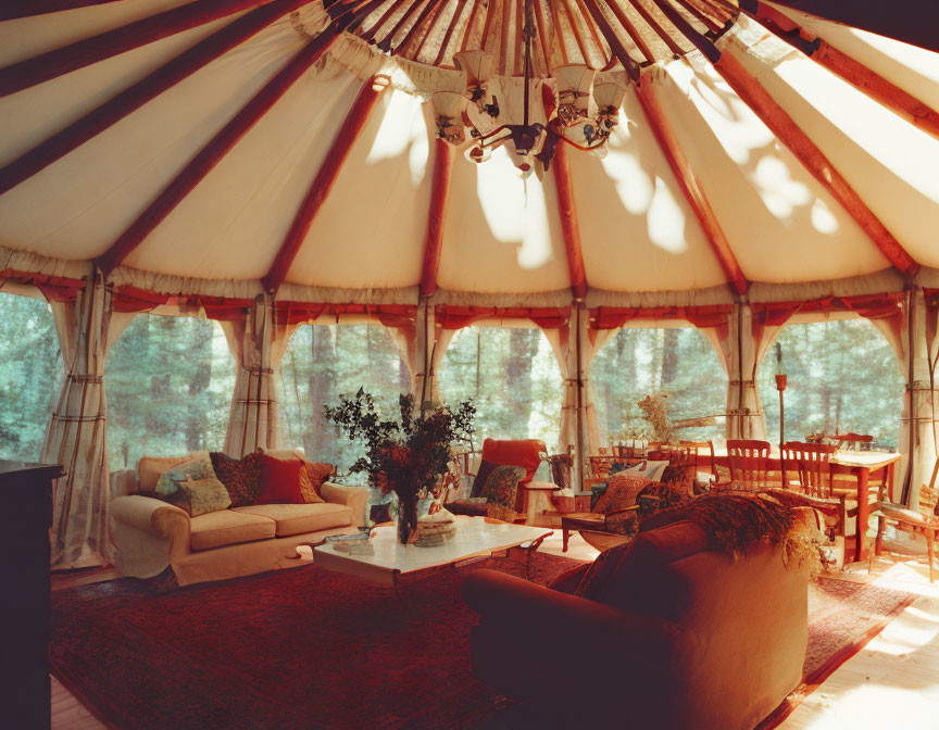 Rustic yurt interior with sofa, chairs, wood stove, dining area in forest setting