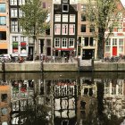 European-style buildings, autumn trees, vintage bicycle, and striped awnings by calm canal