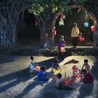 Colorful Street Festival Night Scene with Lanterns, Fire Performance, and Hanging Moss