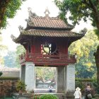 Person walking towards ornate Asian-style pavilion in tranquil garden