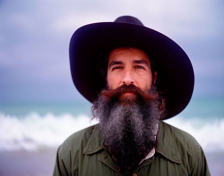 Bearded man in wide-brimmed hat by turquoise sea