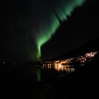 Northern Lights shine over snowy village and river